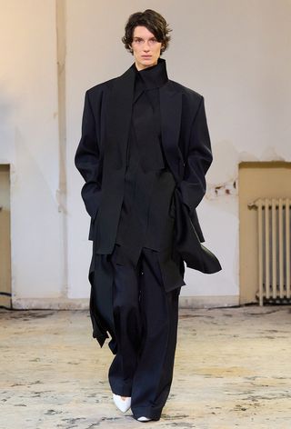 navy color trend shown on Carven's fall runway worn by a model wearing a navy blazer with a black blouse, navy trousers, and white pointed heels