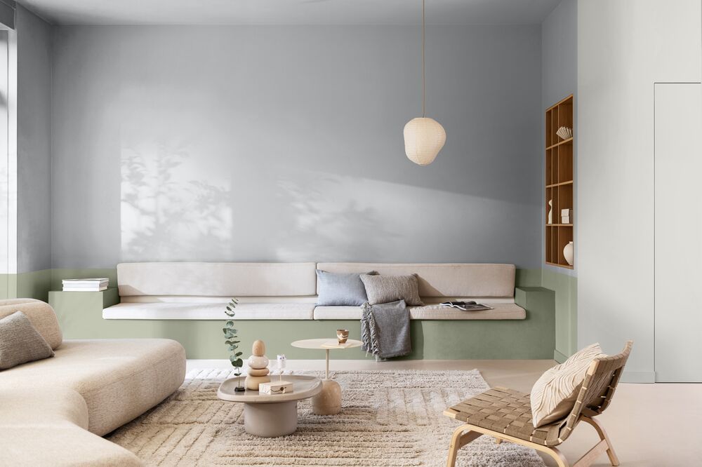 A modern living room with white and wooden furniture and walls that are painted light blue with sage green accents.