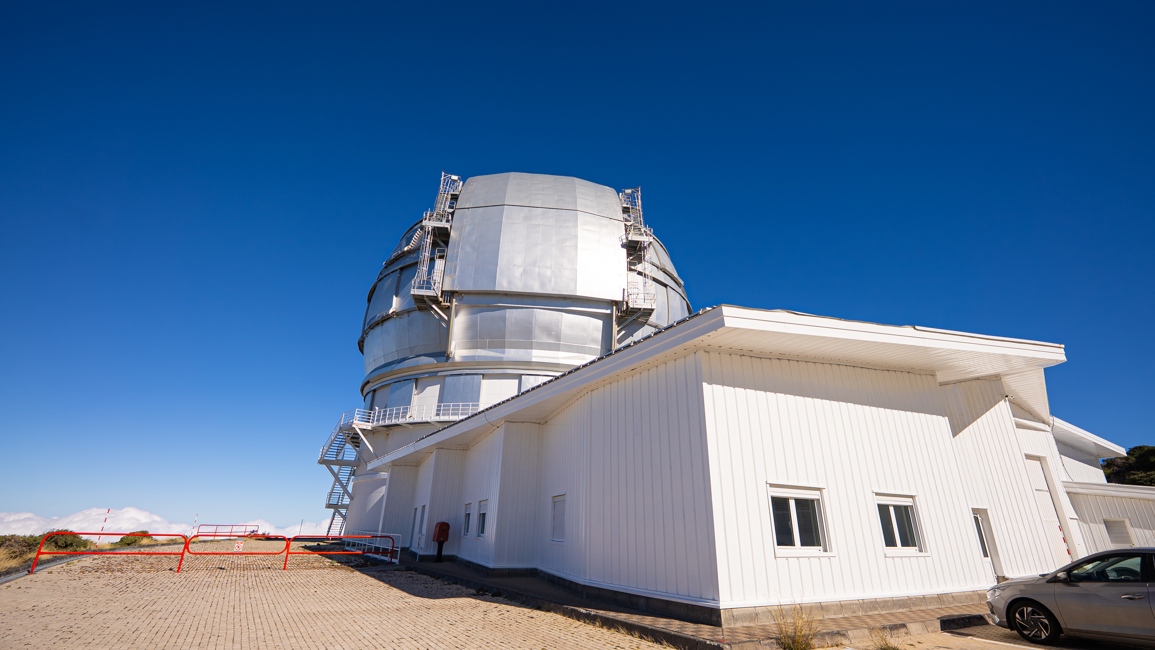 a large telescope dome atop a white building against a blue sky