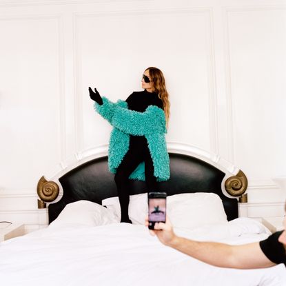 Kelly Wearstler, photographed in July 2022, wearing a Balenciaga top and trousers, a Staud jacket, vintage earrings and Moncler glasses, in her bedroom at Hillcrest, her home in Beverly Hills.