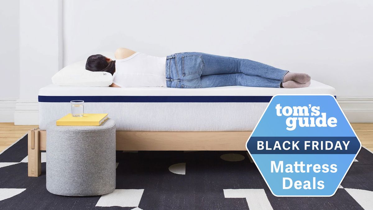 A person lies in a side sleeping position on top of. a Helix Midnight mattress on a bed frame, a Tom&#039;s Guide Black Friday mattress deals graphic (right)