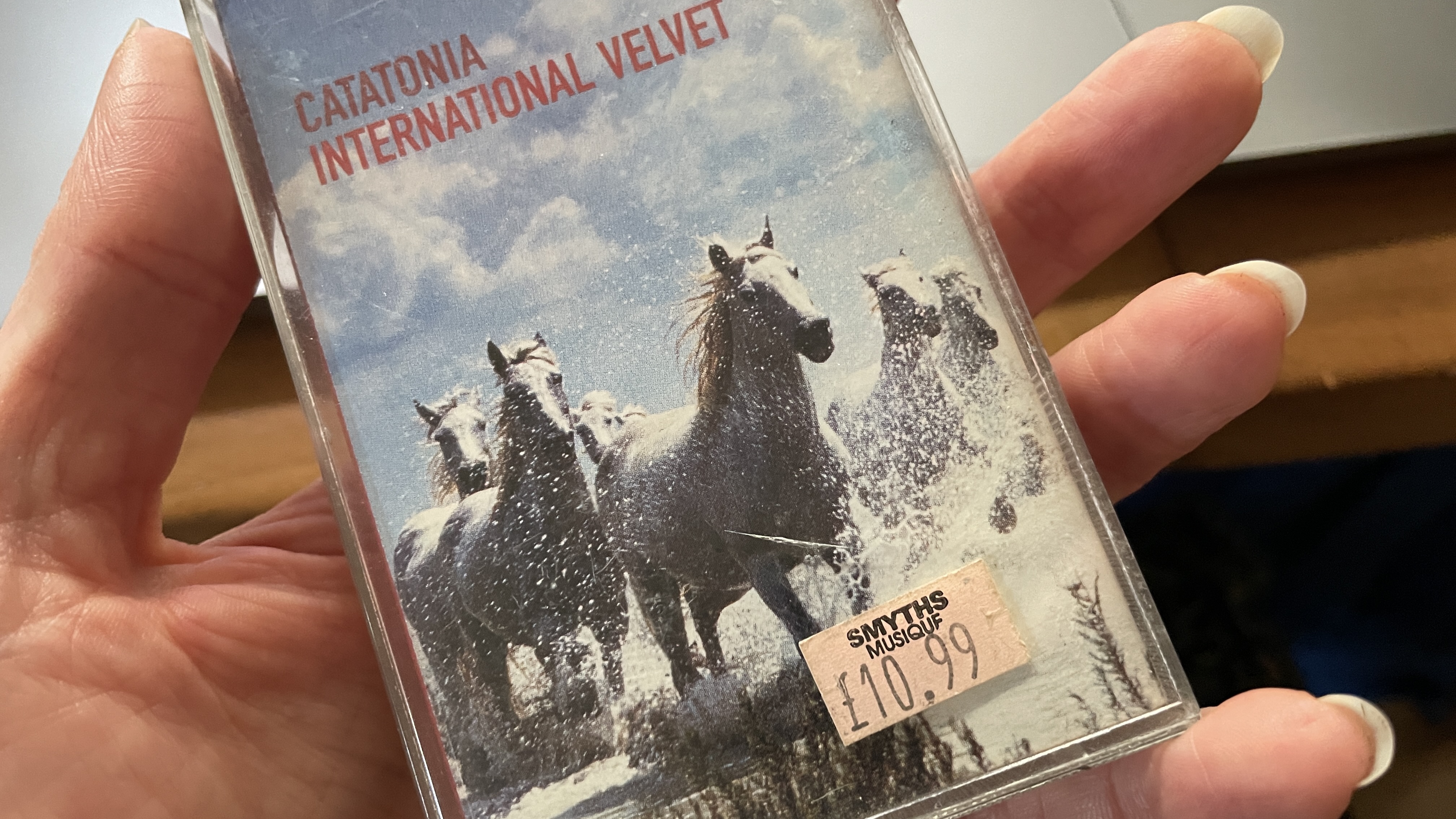 A selection of cassette tapes and a FiiO Walkman, on a wooden surface or held in a hand