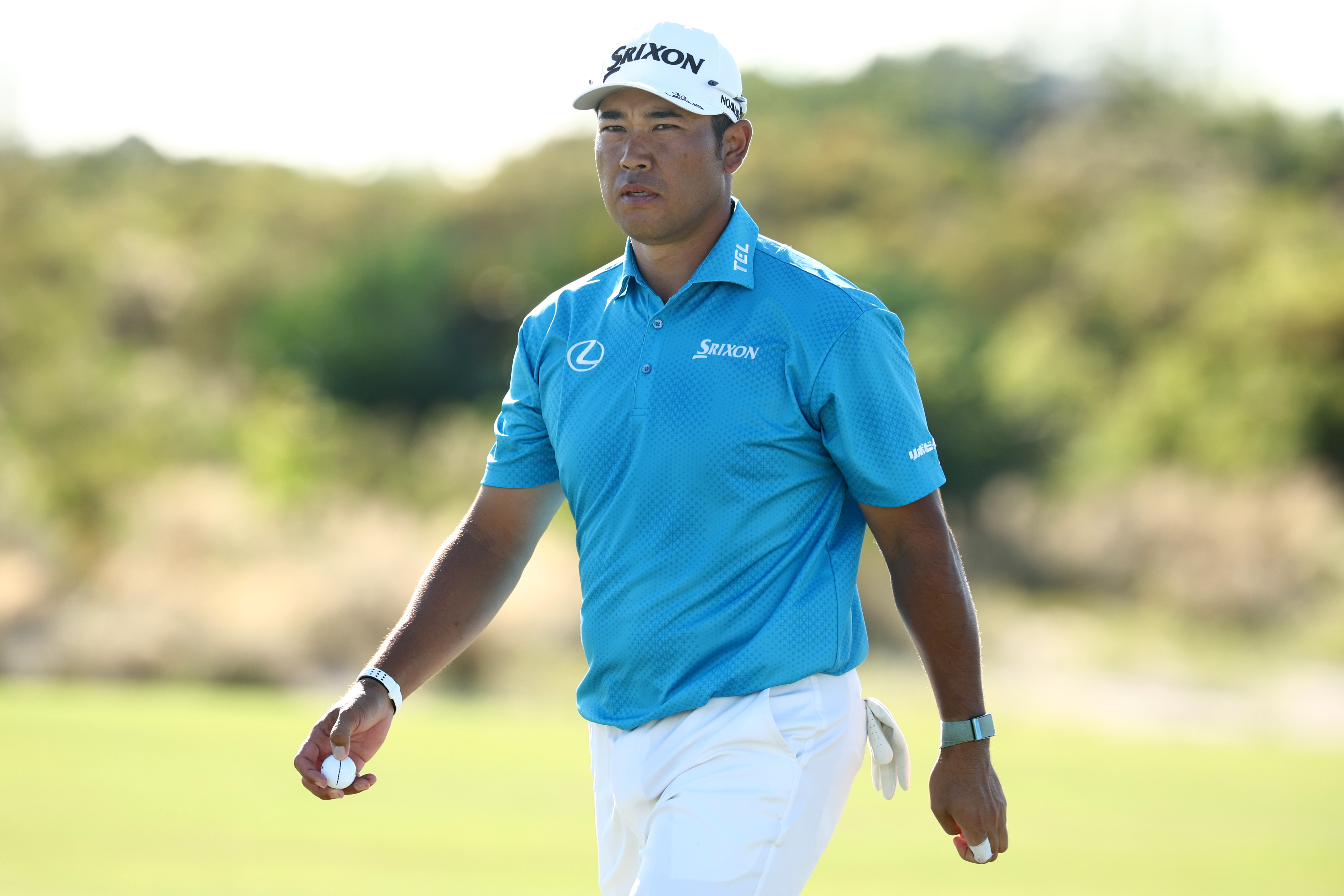 Hideki Matsuyama walks off the green holding a golf ball