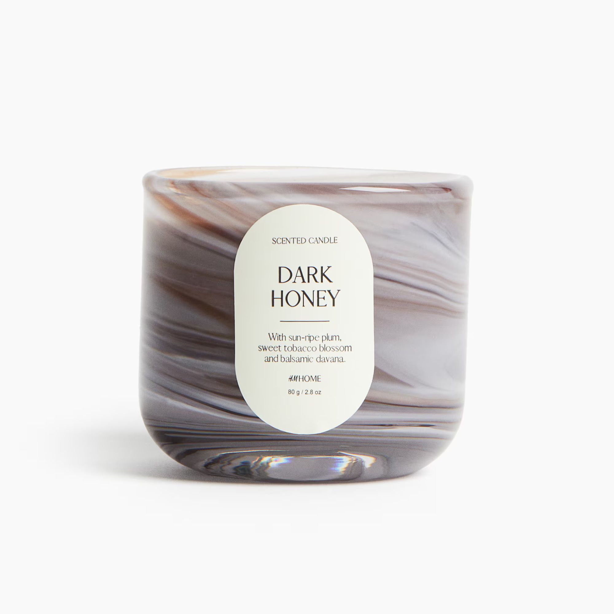 Small scented candle in glass holder with swirling white and brown effect