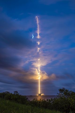time lapse image of a rocket leaving a streak behind as it lifts off from the launch pad