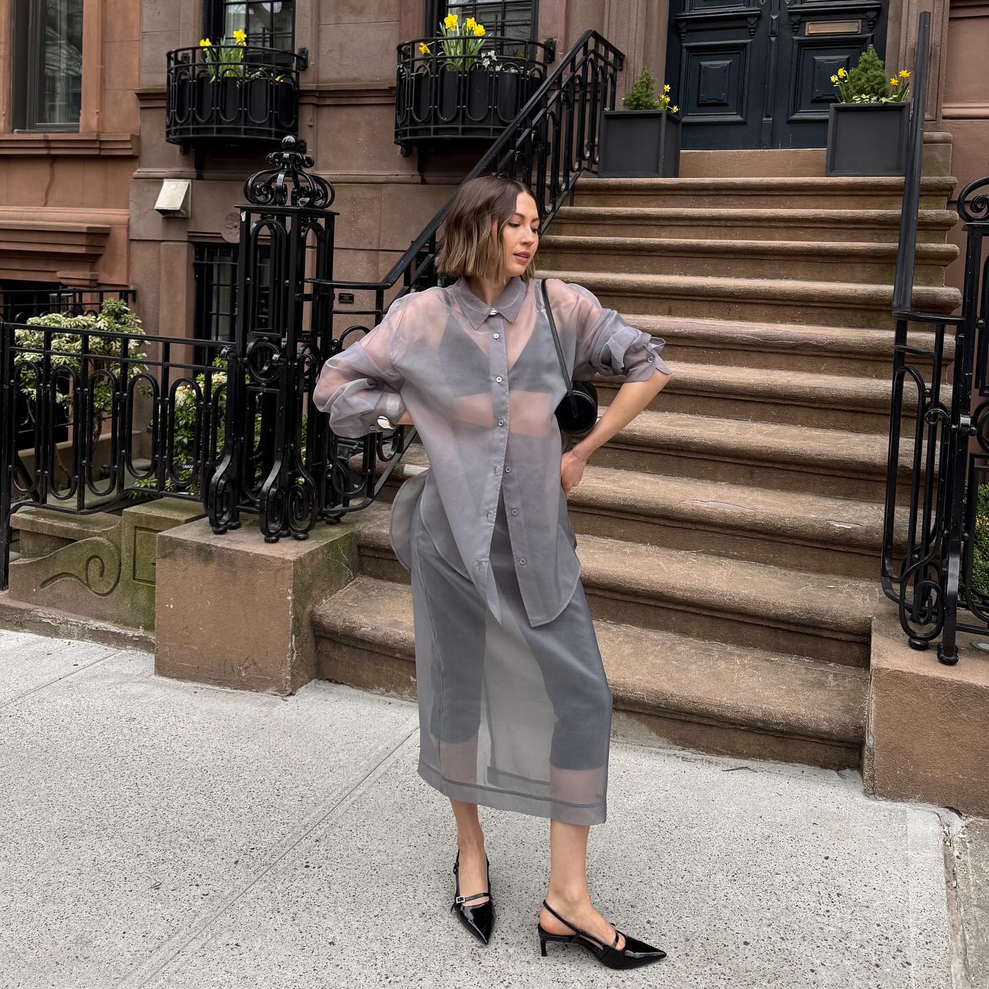 An image of @trendingwithtinsley wearing a sheer blouse.