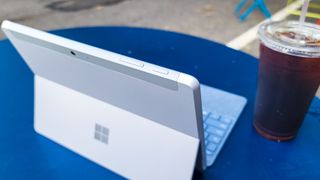 Surface Go 3 on a blue table outdoors next to a cup of iced coffee
