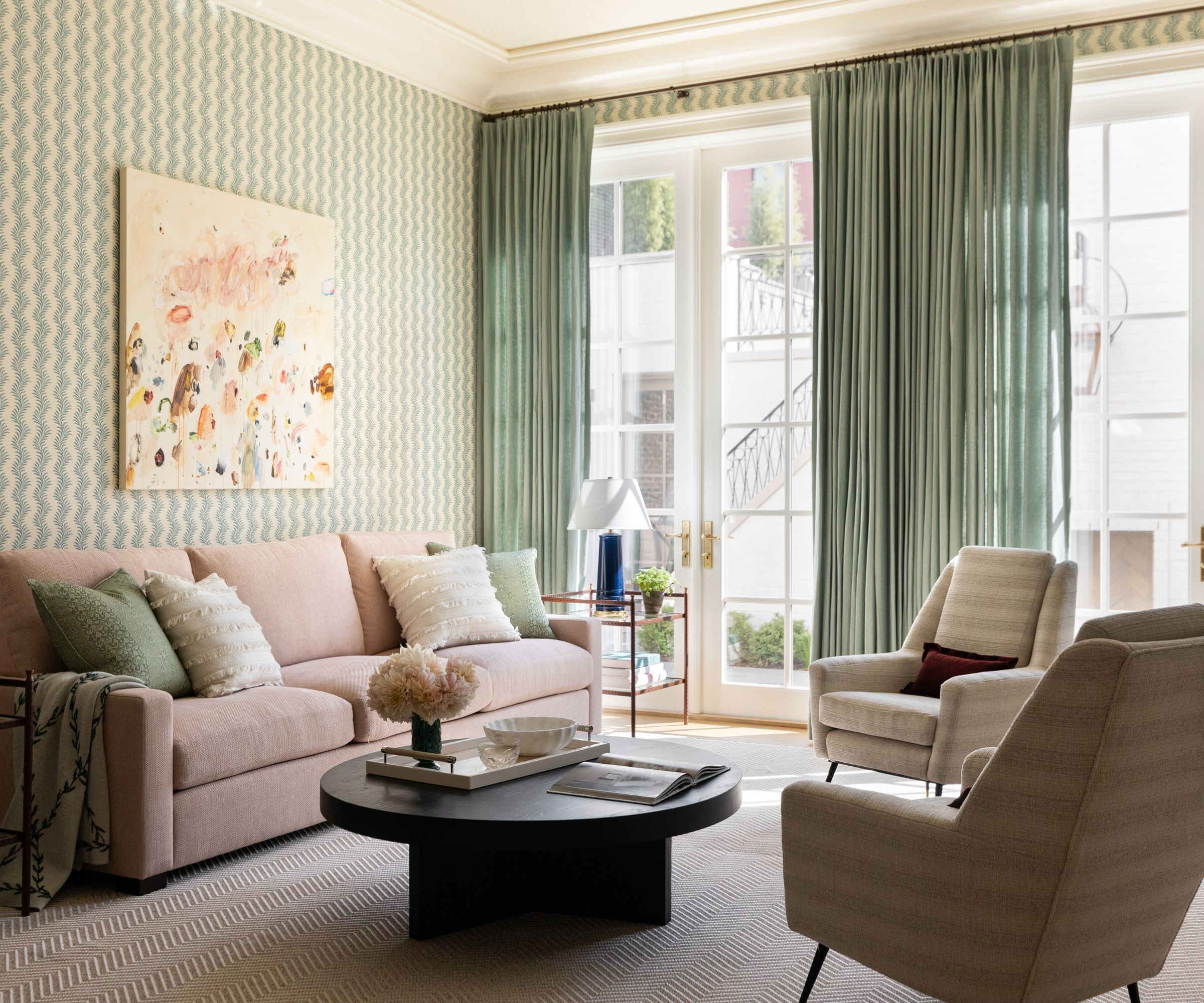 A traditional living room with pale green wallpaper, green curtains with large French doors, and a pale mauve sofa.