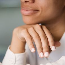 Manicure and pedicure tools - image of a woman with her chin on the back of her hand showing her beautiful nails - gettyimages1468504863