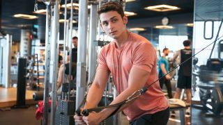 Man performs cable flye chest exercise in gym