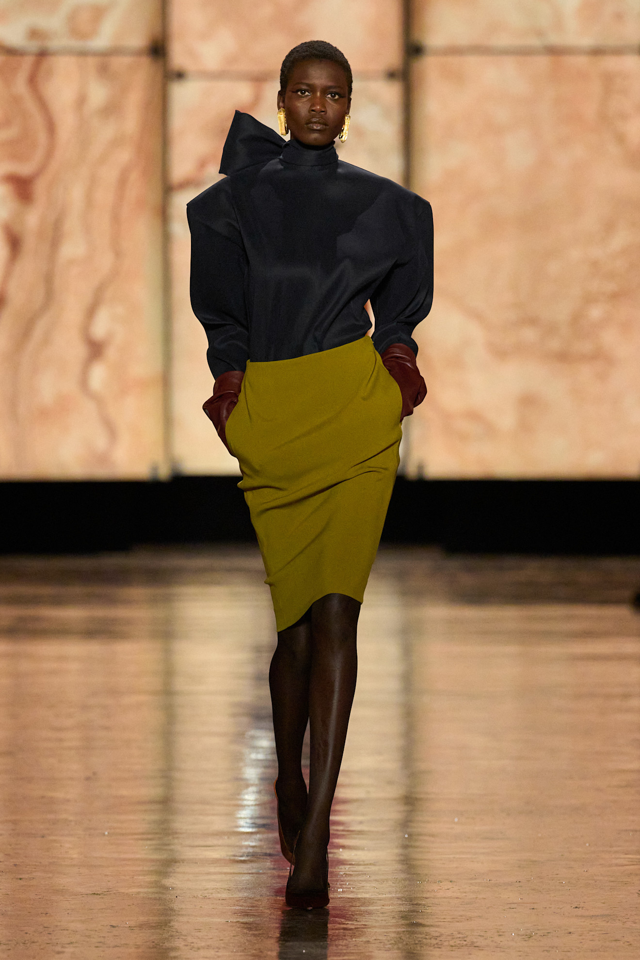 A model wears a knee skirt and satin blouse on Saint Laurent&#039;s autumn/winter 2025 runway