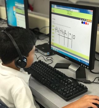 Boy wearing headphones works on computer learning program