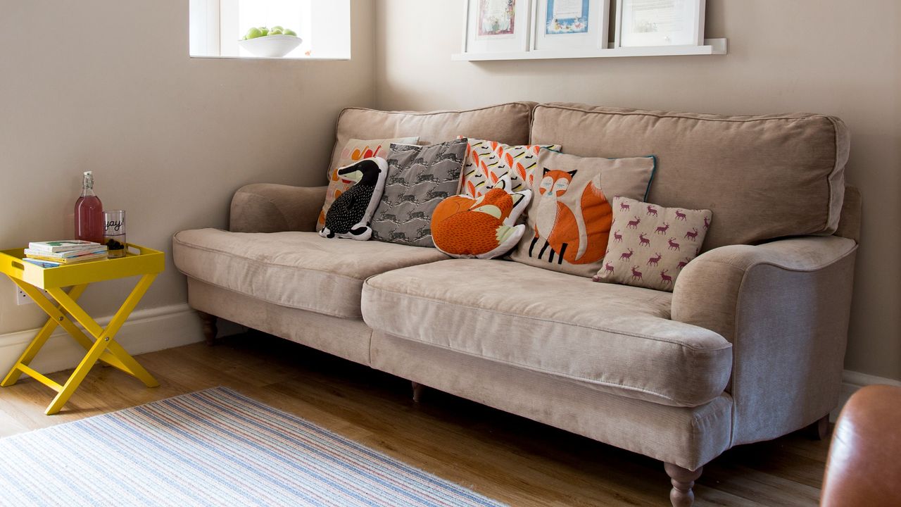 A living room with a beige suede sofa and fox-shaped cushions