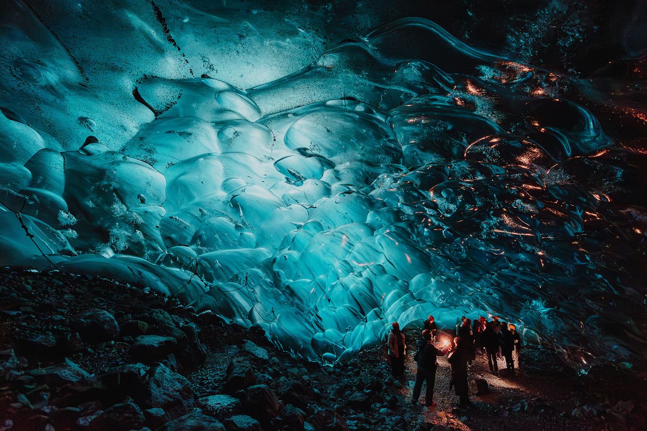 Photograph taken at the Amazon Influencer Program in Iceland for the BRYANT brand, by Luke Dyson. It shows guests exploring a glacier cave illuminated from within.