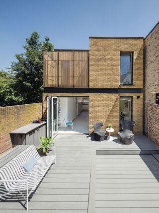 small passivhaus clad in brick with a deck