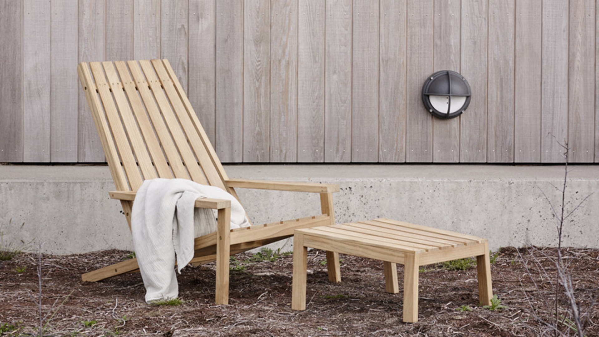 A wooden outdoor chair with reclining backrest and footstool