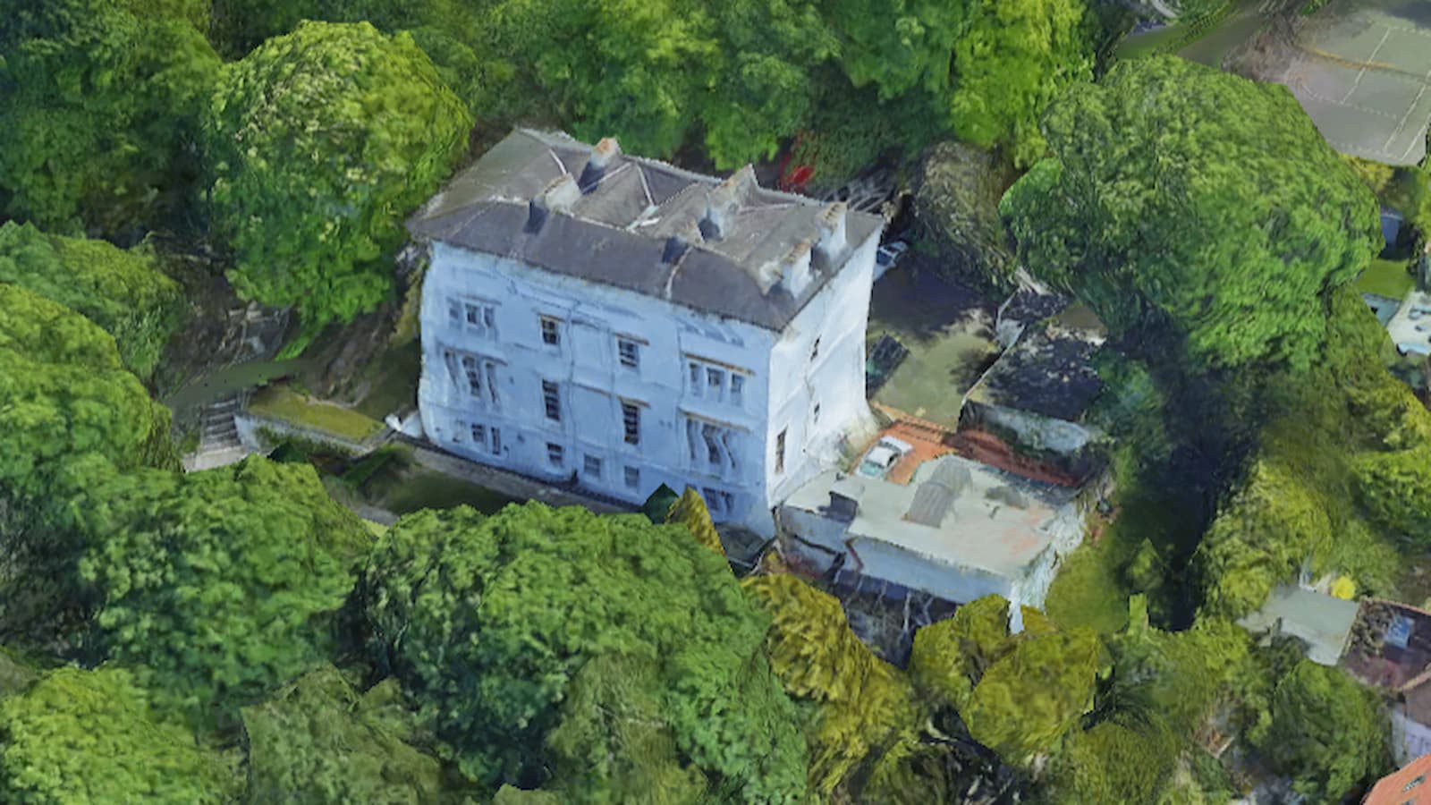 A white mansion surrounded by trees seen from above