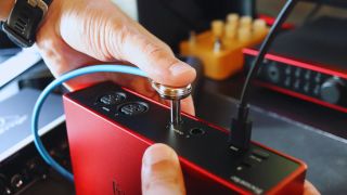 A man pushes a patch cable into the output of an audio interface