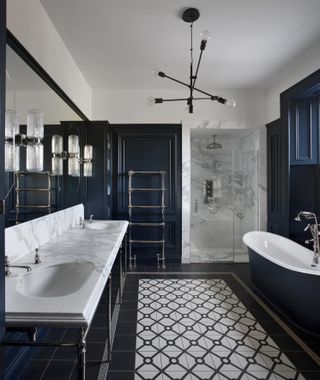 A dark blue bathroom with marble worktops, a shower, and a patterned tiled floor