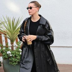 Hailey bieber wears a black leather trench coat, leopard bag and black t-shirt.