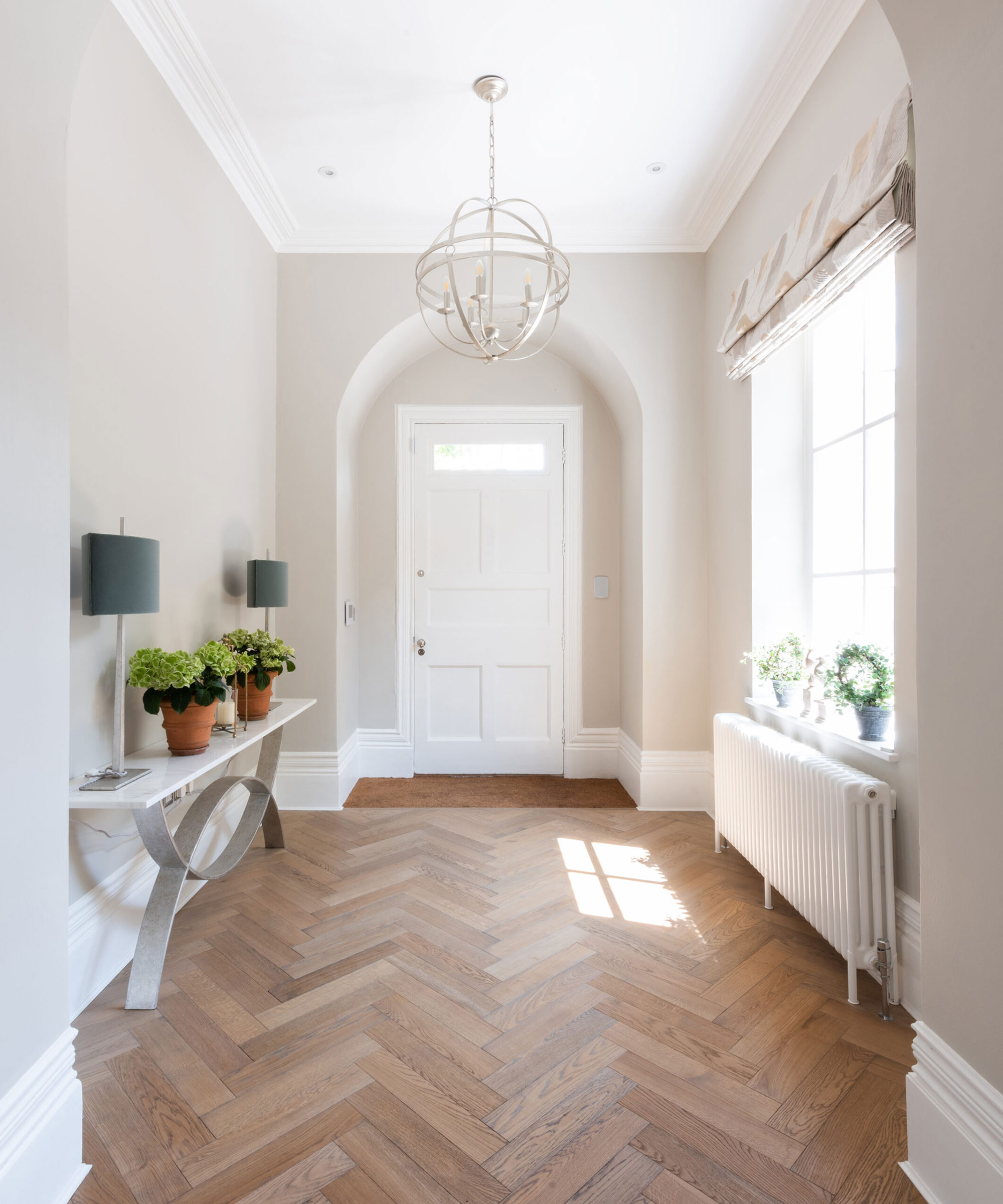 large entrance hallway with high ceilings and herringbone wooden flooring