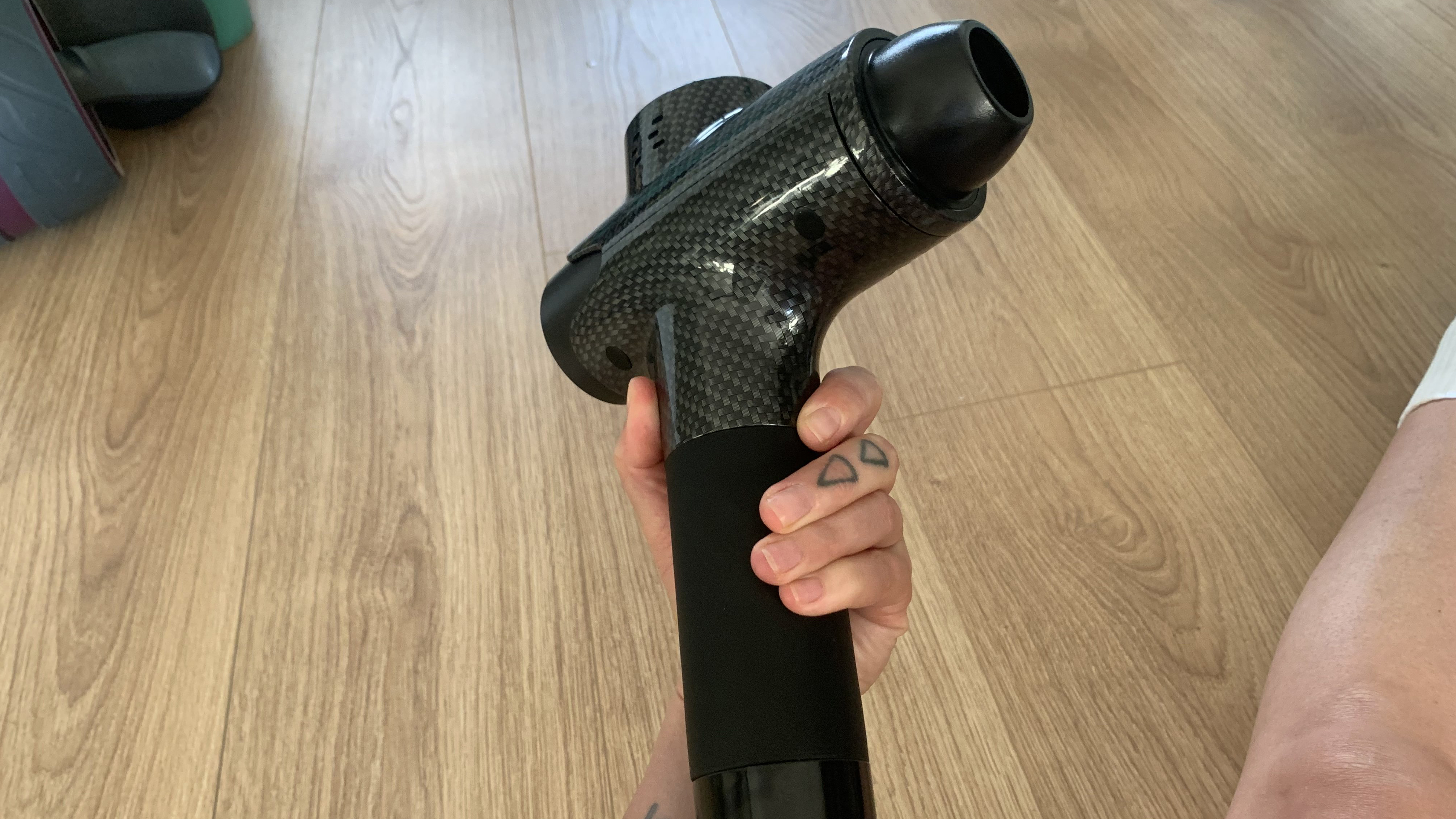 Lairlux massage gun being held in tester's hand