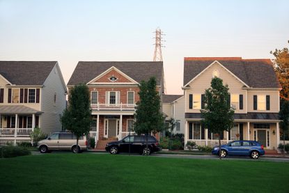 Three houses in a middle-class neighborhood with cars parked out front