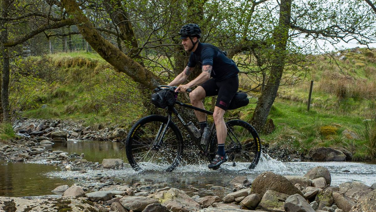 A man riding through a river on a bikepacking bike