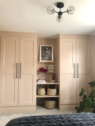 A wardrobe from floor to ceiling painted peach in a bedroom