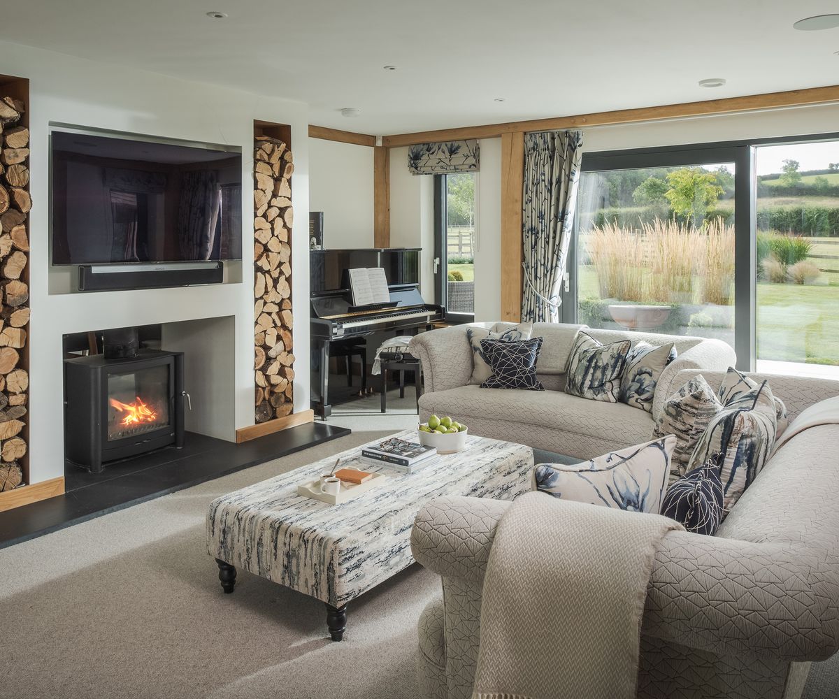 Living room with two large pale sofas in front of a log burning fire and tv