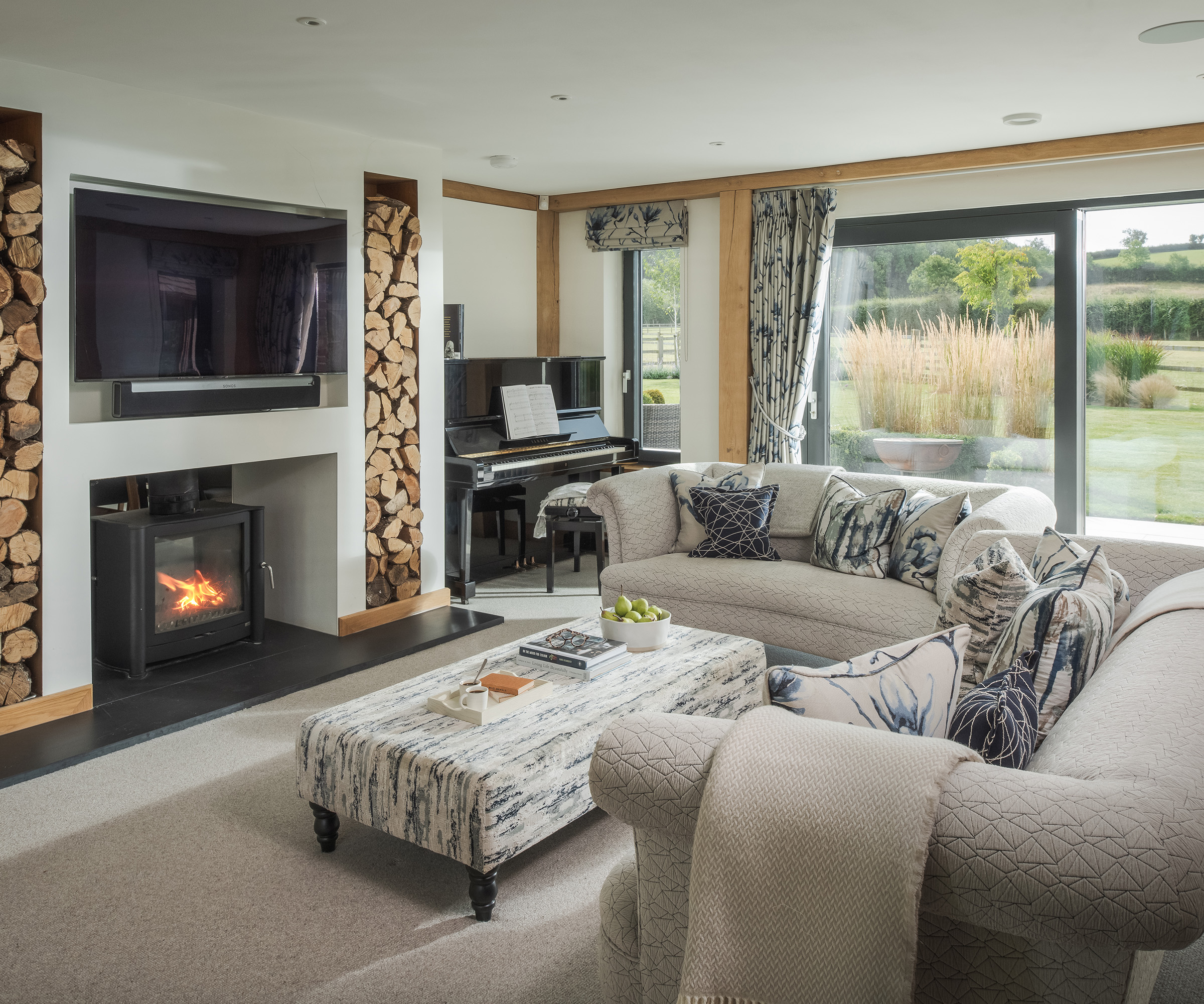 Living room with two large pale sofas in front of a log burning fire and tv
