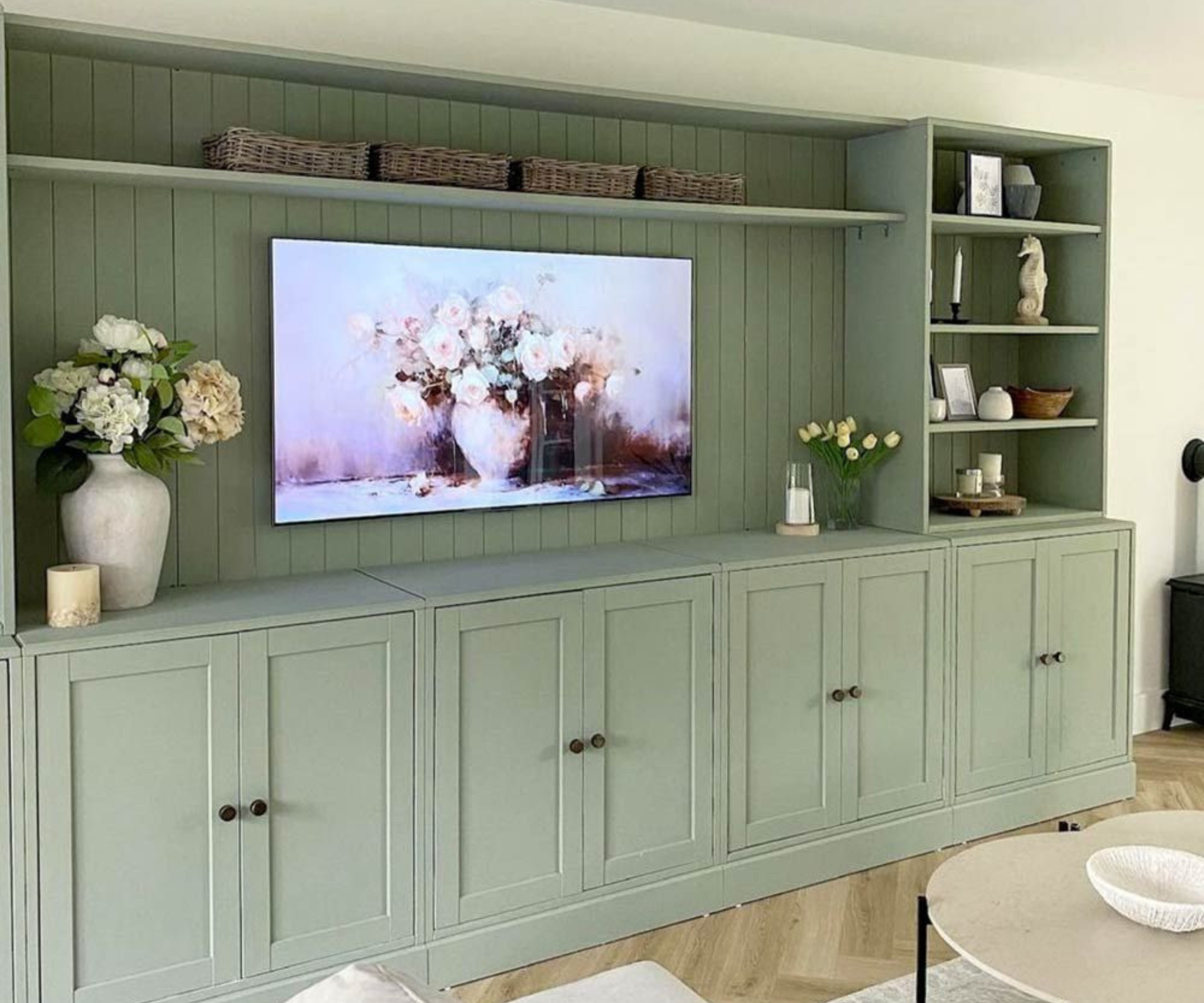 Sage coloured media wall with panels behind tv and a mix of closed and open shelf storage
