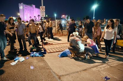 Concertgoers attending to wounded at Las Vegas music festival after a mass shooting.