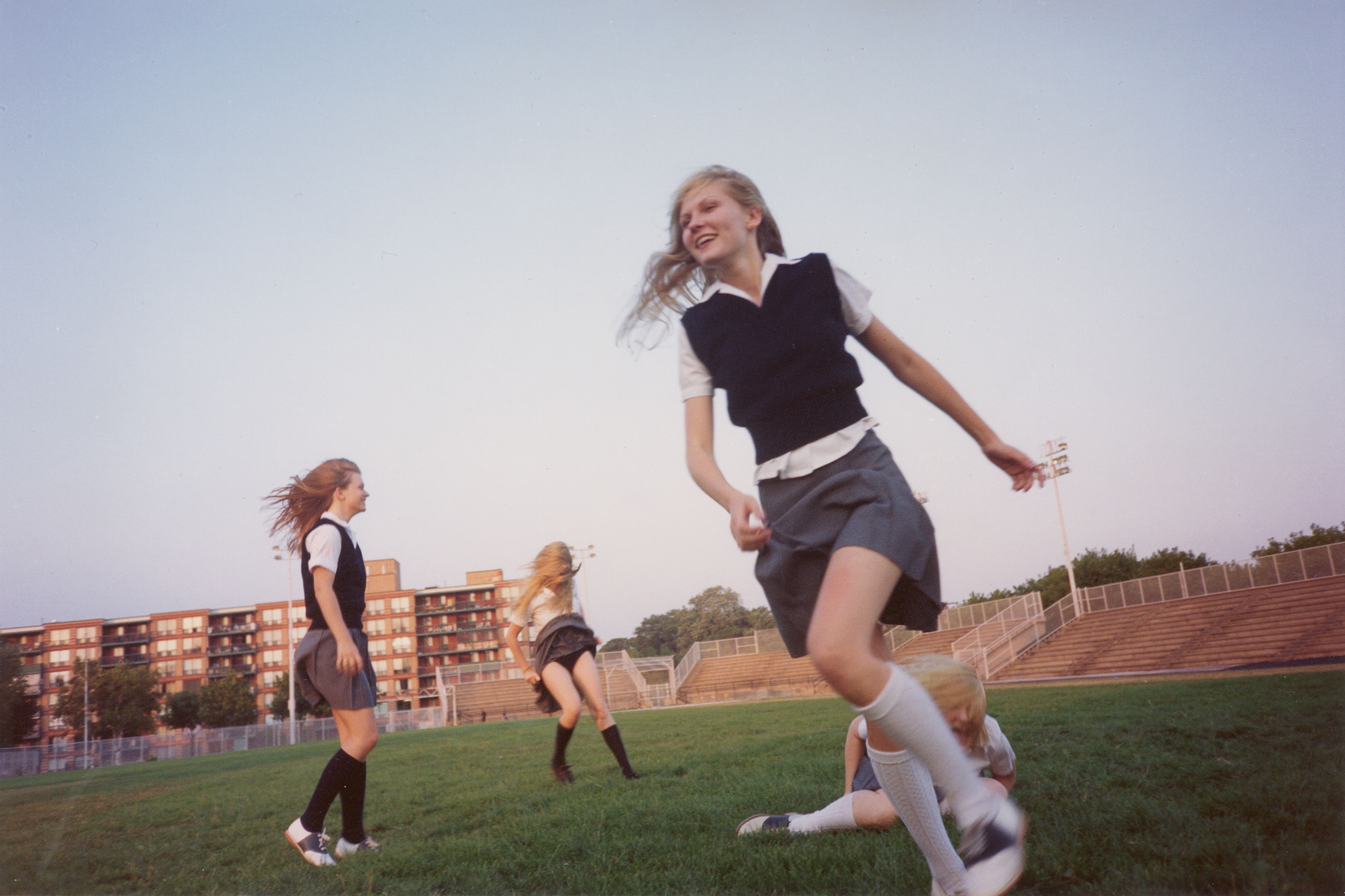 kirsten dunst as lux lisbon and the other lisbon girls in school uniforms running around a football field in the virgin suicides