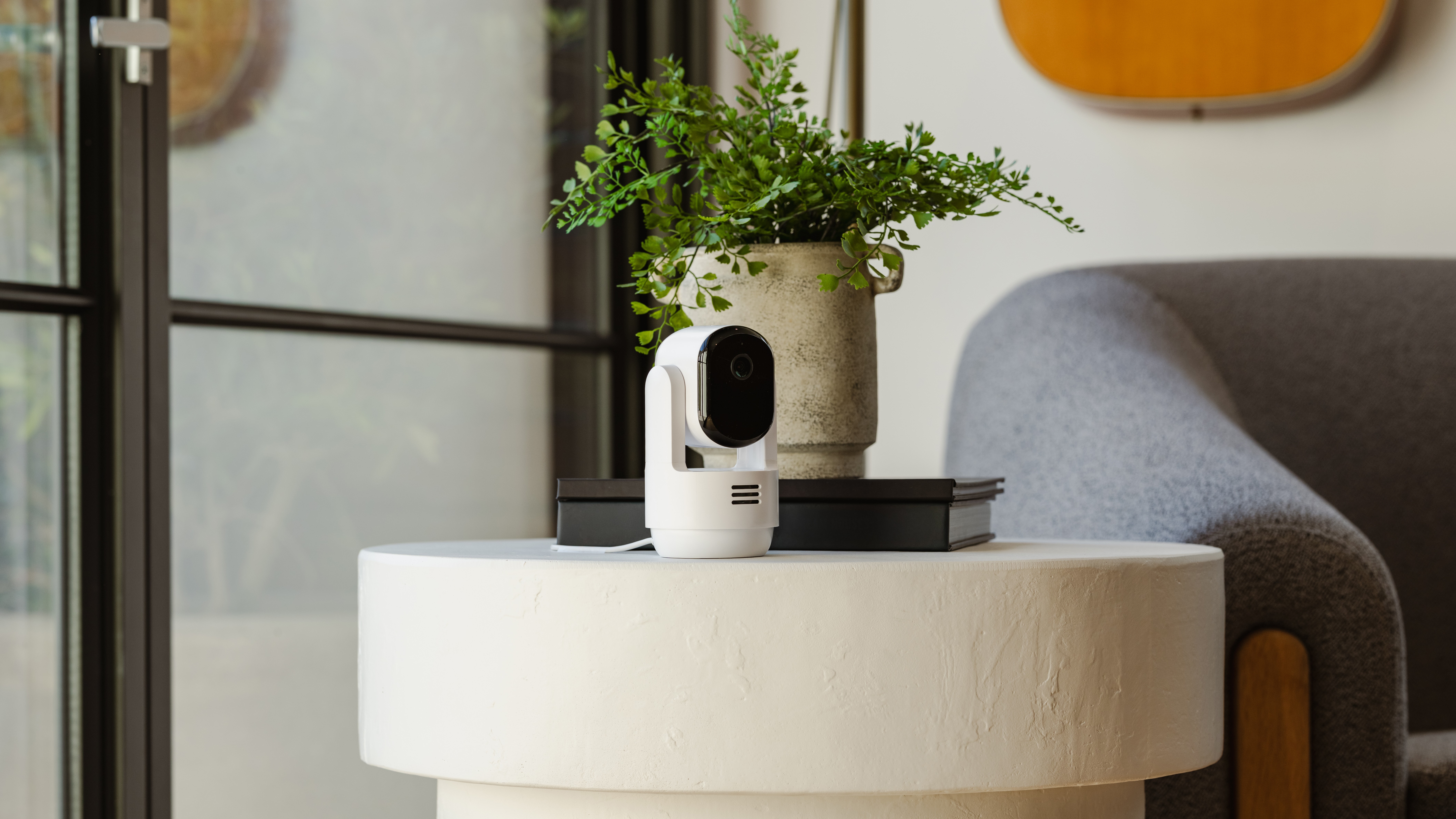 Arlo Pan and Tilt camera on an end table near a plant and a couch