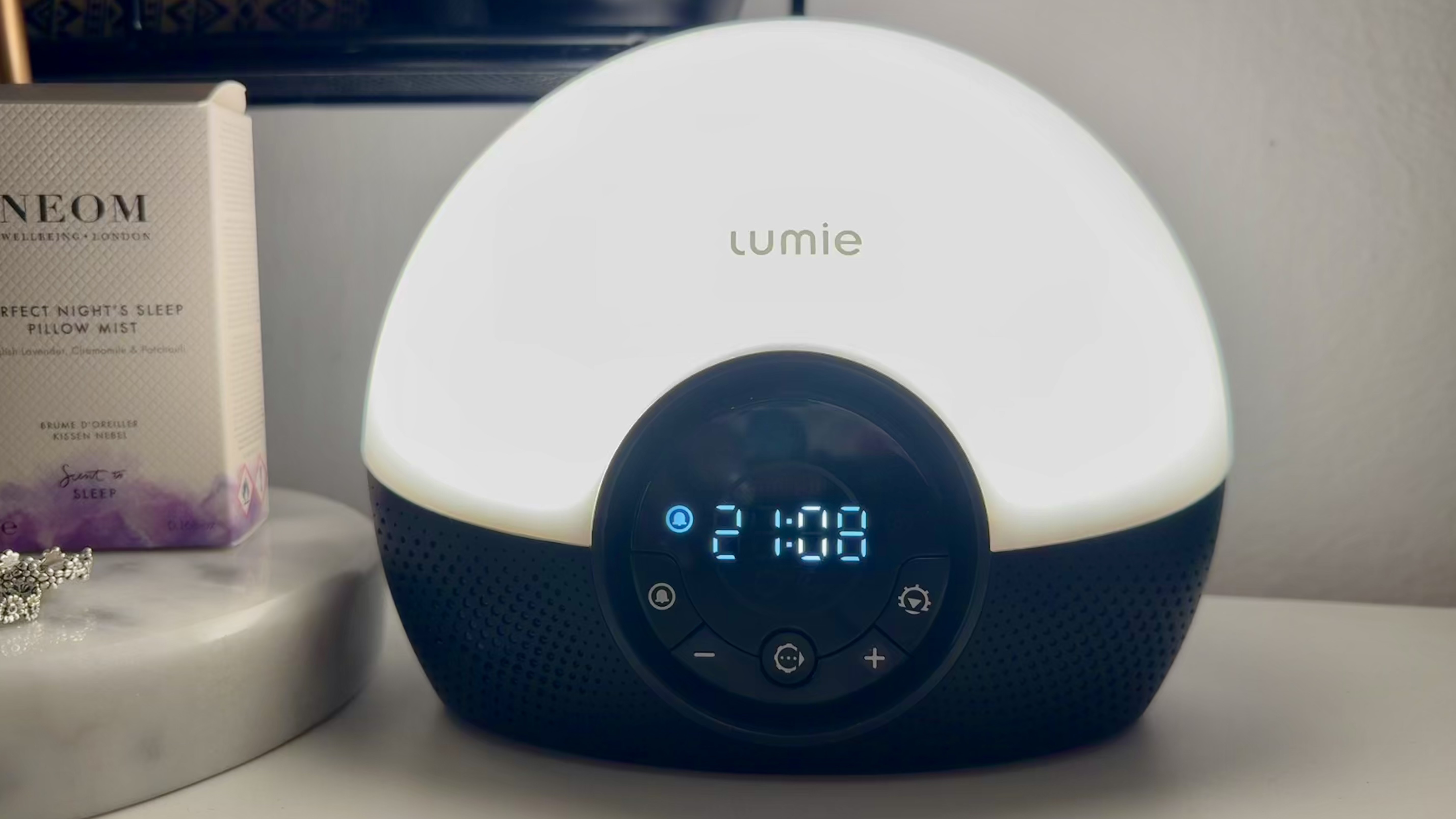 Lumie Bodyclock Glow 150 lit up with digital clock displaying 21:08 on bedside table