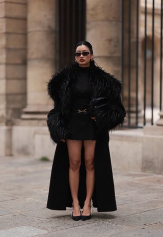 woman wearing a faux fur coat, turtleneck, shorts, and heels