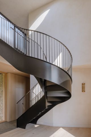 capability house with minimalist interiors of stone and timber and a twisting metal staircase