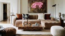 low slung brown sofa in a white living room with burl wood coffee table in the middle