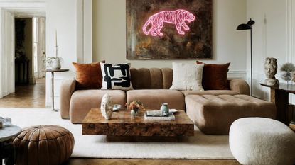 low slung brown sofa in a white living room with burl wood coffee table in the middle