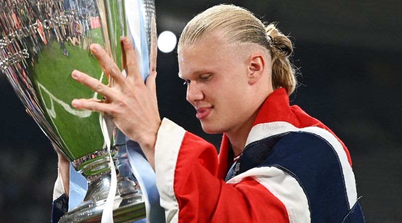 Erling Haaland, draped in the Norwegian flag, celebrates with the Champions League trophy after Manchester City&#039;s treble triumph in June 2023.