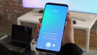 En hand håller upp en Galaxy S8 som kör Bixby.