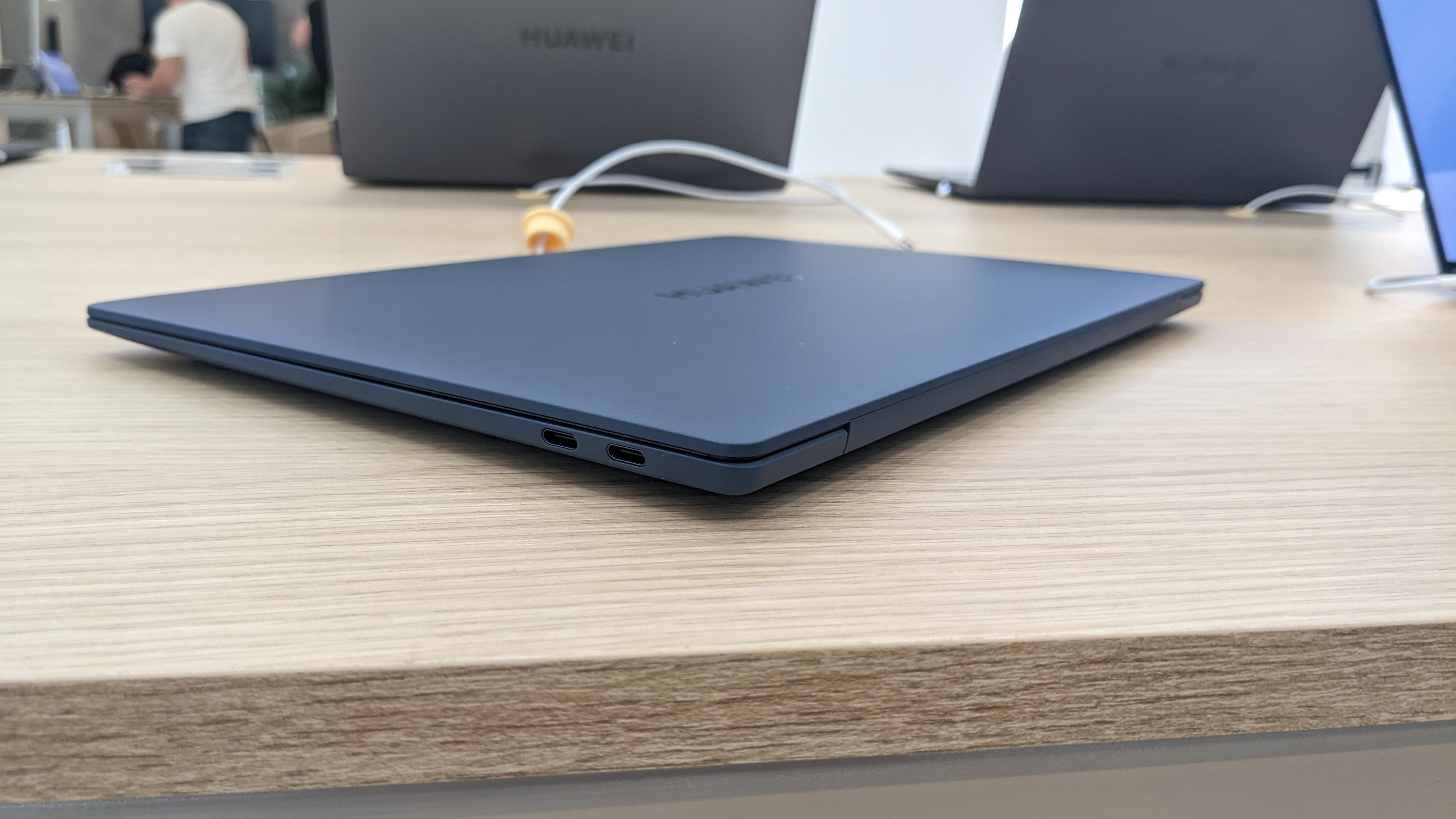Huawei MateBook X Pro (2022) on a wooden desk with charger plugged in.