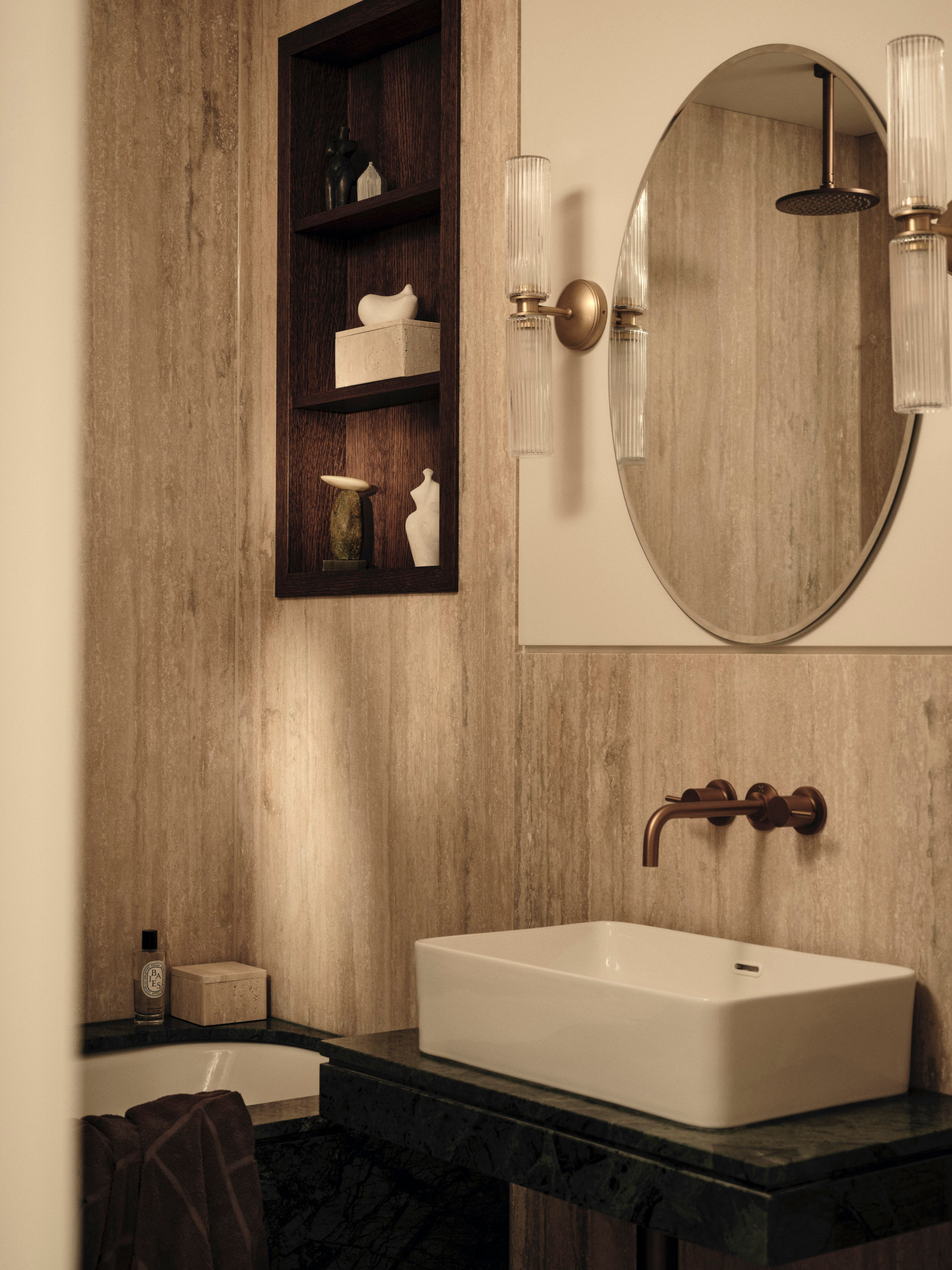 Bathroom with beige stone-covered walls, square sink and aged brass tap