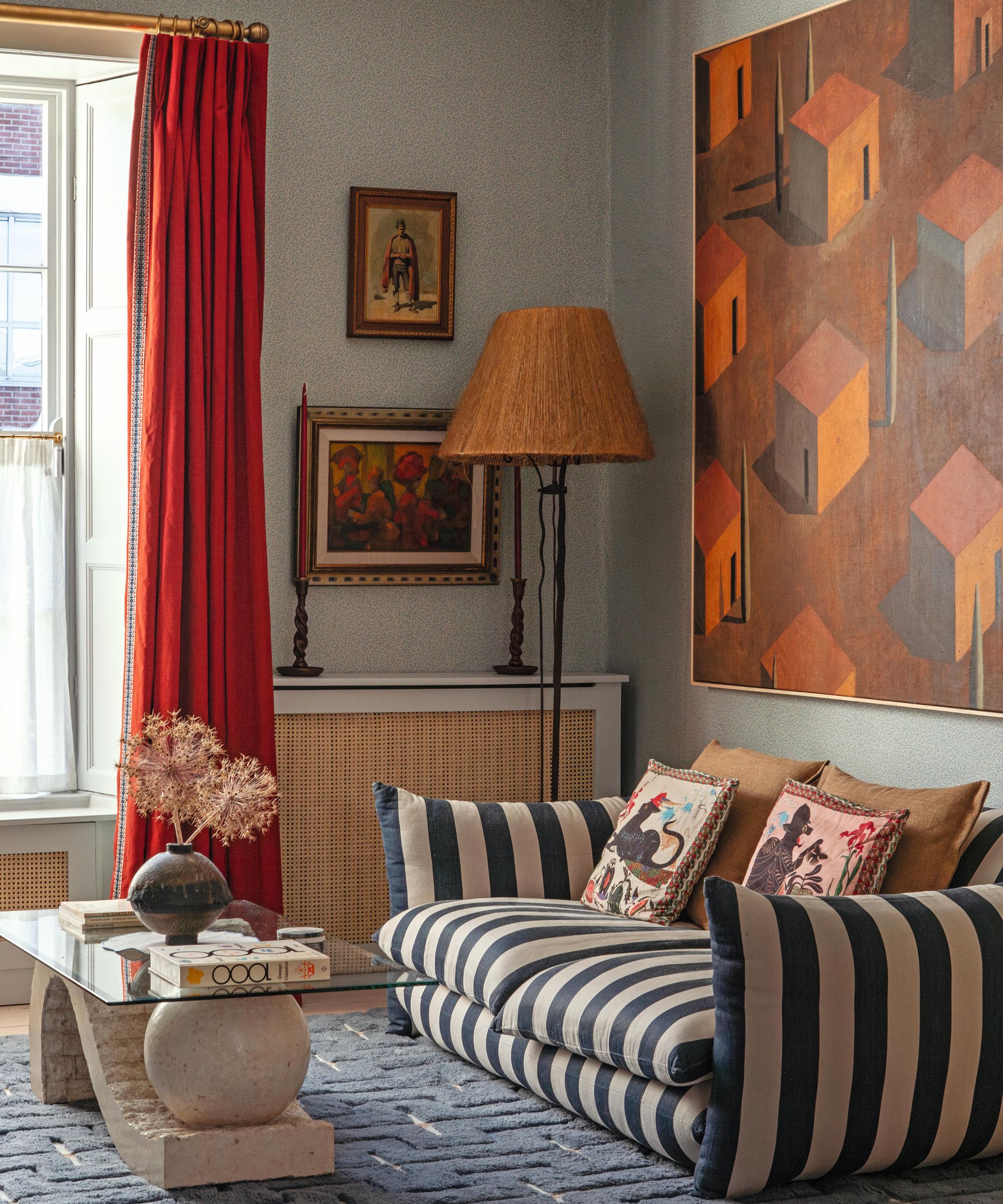 a Victorian living room painted pale blue with a large striped couch, eclectic mix of statement art and a blue tufted rug