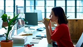 Woman takes a work break at her desk with a hot drink