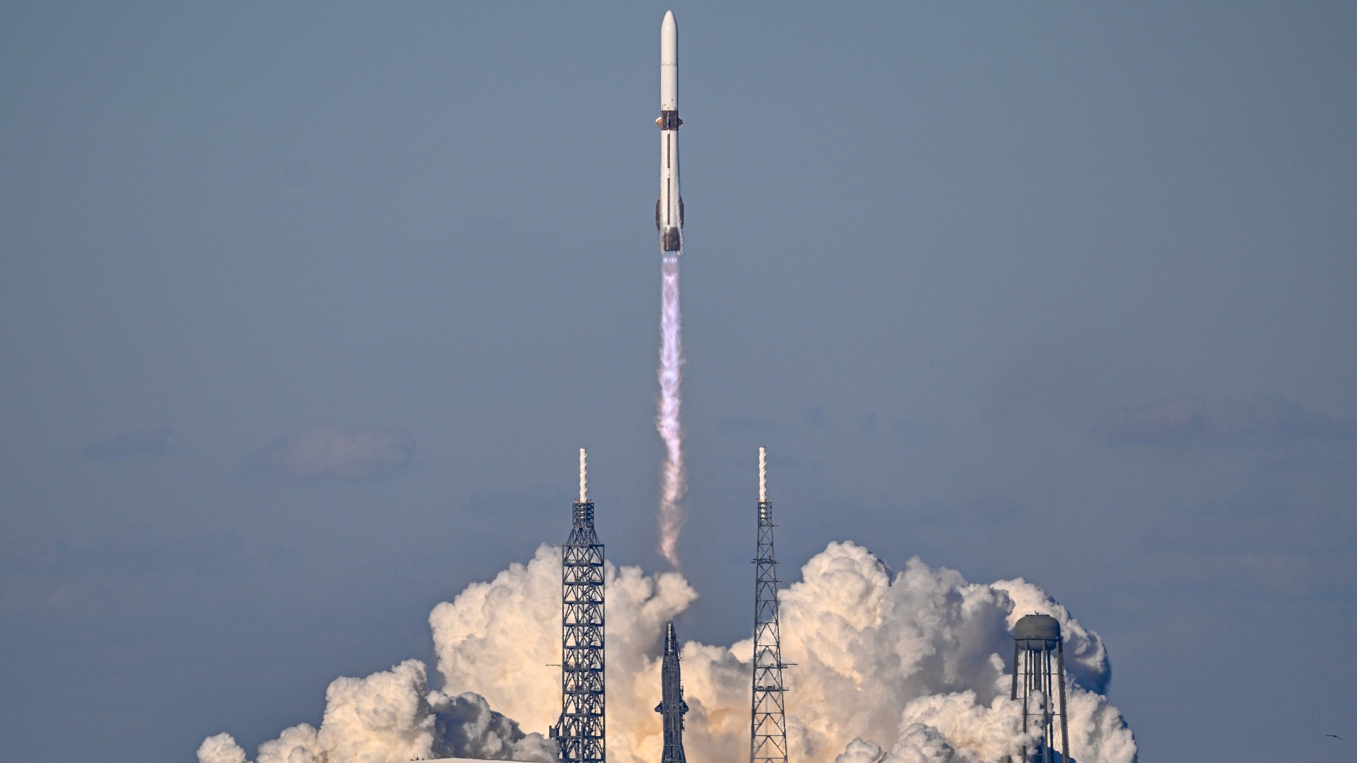 a white and blue rocket lifts off above a plume of fire