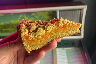 slice of coffee cake held up with a jukebox in the background
