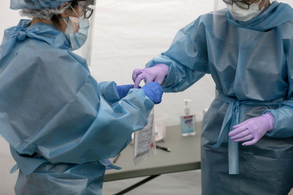 Health workers handle a COVID-19 swab test on May 8, 2020 in Greenwich