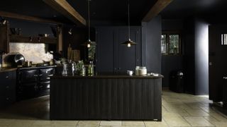 Black kitchen with black kitchen cabinets and timber beams